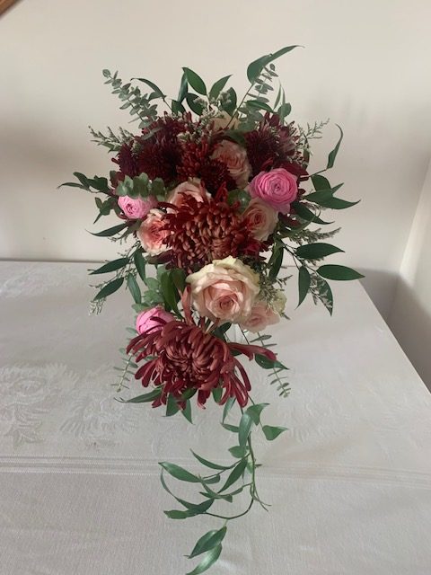 Burgundy mum, pink rose, and greenery cascade bouquet