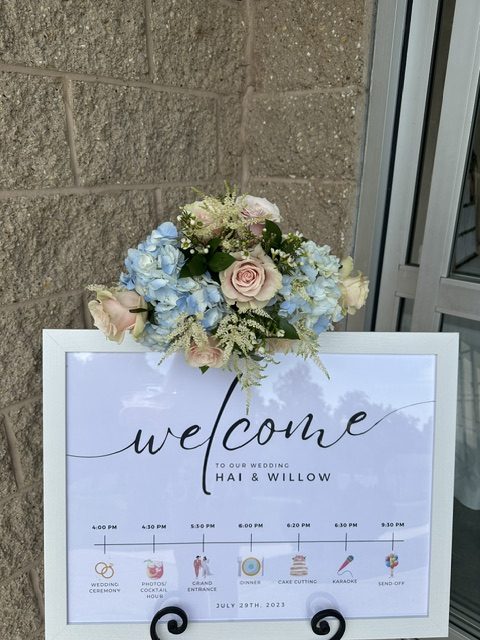 Light blue hydrangea and pink rose arrangement on a welcome sign