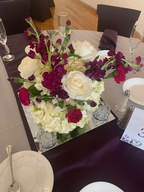 White hydrangea, purple stock, and white rose centerpiece